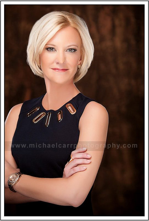Professional Photographer Houston Houston modern casual headshot of a business professional wearing a black sleeveless dress with gold neck dress accents