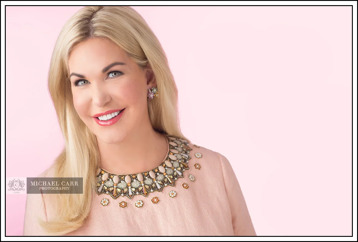 Professional Photographer Houston Houston modern casual headshot of a professional woman wearing a blush blouse against a soft pink background