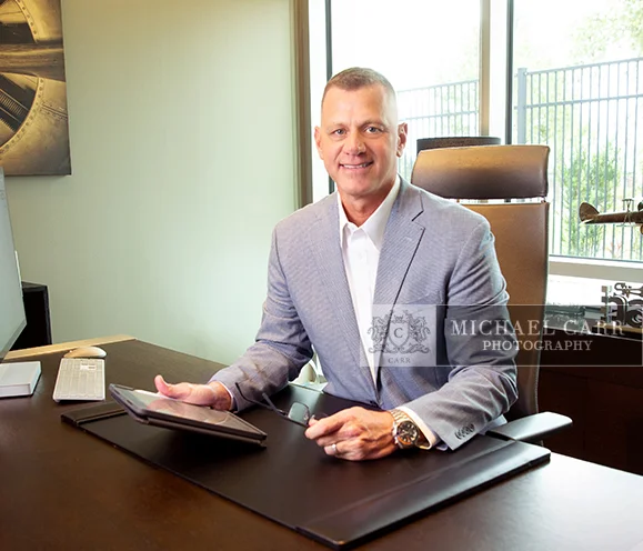 Professional Photographer Houston Executive seated at an office desk during a personal branding photography session by Houston Personal Branding Photographer Michael Carr Photography