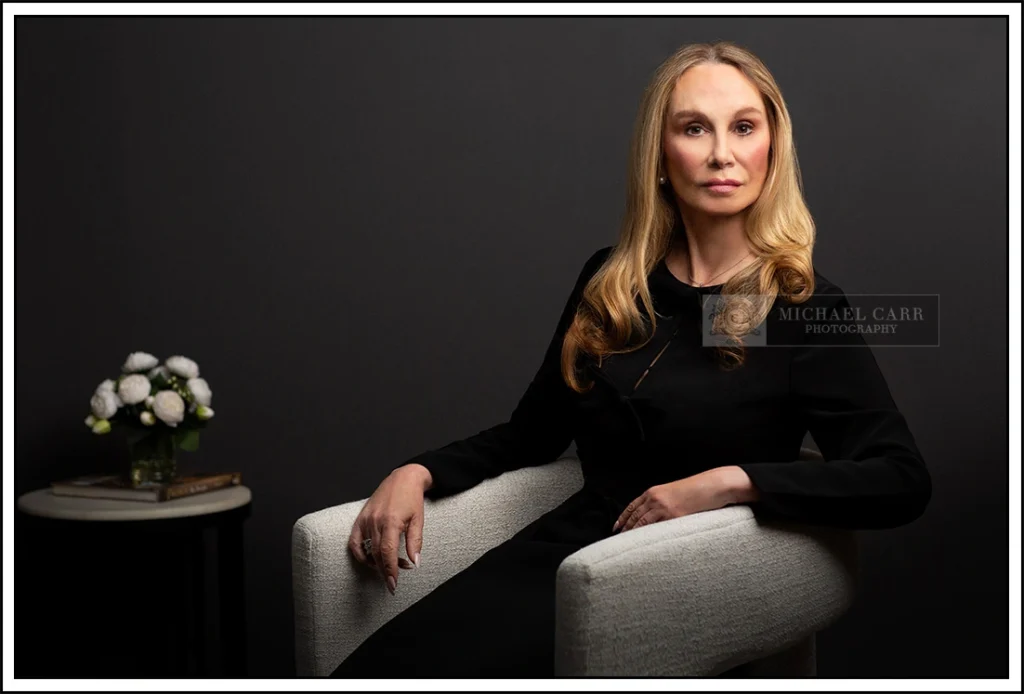 Woman dressed in black seated in a chair for a fine art portrait in studio